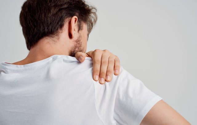 man touching painful shoulder
